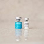 Close-up of Xeomin and Dysport bottles reflecting on a surface, shot indoors.