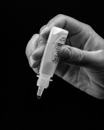 Hand holding eye drops, ready to administer.