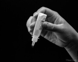 Hand holding eye drops, ready to administer.