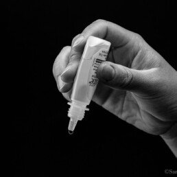 Hand holding eye drops, ready to administer.